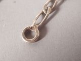silver chain with a ring on it on a white surface