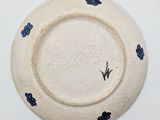 a white plate with blue flowers on it on a white surface