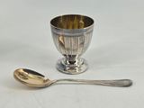a silver cup and a spoon on a white table