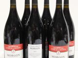 six bottles of red wine are lined up on a white surface