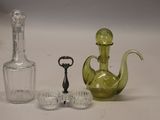 trois objets en verre différents posés sur une table avec une bouteille