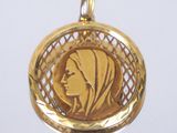 une image représentant un pendentif en or avec le visage d'une femme au centre