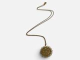 un collier en or avec une boule suspendue à une chaîne, sur fond blanc