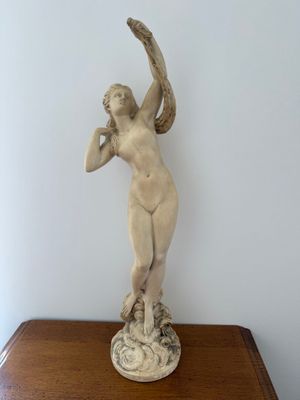 a statue of a woman holding a bird on top of a table