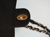 black leather purse with a gold chain and a ring on it