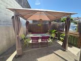une terrasse avec une table et des chaises sous un auvent