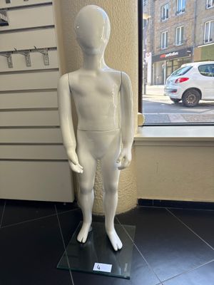 un mannequin blanc debout devant une vitrine