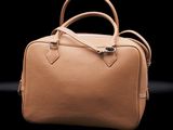 a tan leather handbag on a black background