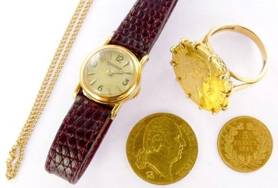 a gold watch and a gold coin on a white surface