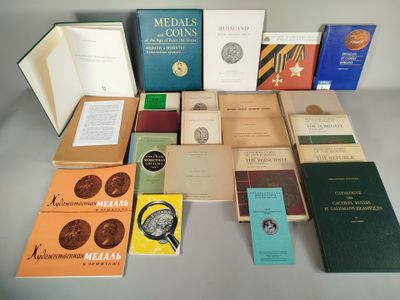 Plusieurs livres sont empilés sur une table où se trouvent également une horloge et d'autres livres