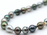 a close up of a strand of multi colored pearls on a white surface