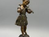 une statue en bronze représentant une jeune fille jouant du violon, posée sur un socle