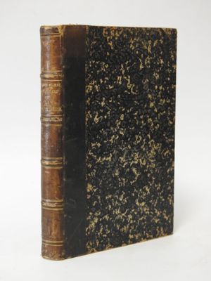 an old book sitting on top of a white table next to a white wall