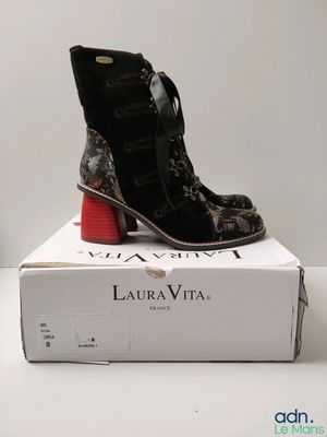 La boîte est posée sur la table, avec une paire de chaussures dessus.