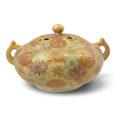 a gold and red vase with a lid on a white surface