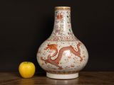 a vase with a dragon on it next to an apple