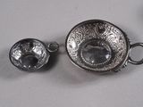 tasse et soucoupe plaquées argent, accompagnées d'une cuillère, sur un fond blanc