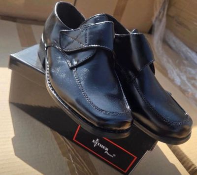 des chaussures en cuir noir ornées d'un nœud, posées sur une boîte posée sur une table