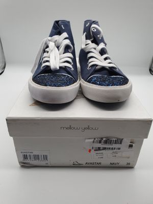 des baskets bleues et blanches pailletées posées sur une boîte