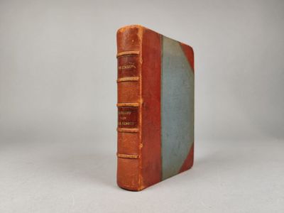 un vieux livre posé sur une table à côté d'un mur blanc