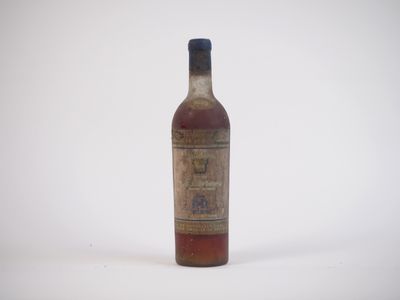 une vieille bouteille de whisky posée sur une surface blanche