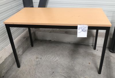 une table en bois sur laquelle est posée une pancarte, devant un immeuble
