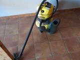 a yellow and black vacuum on the floor next to a window