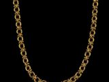 a gold plated chain necklace with a circular link on a black background