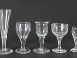 cinq verres à vin et un vase posés sur une table