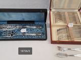 deux pièces d'argenterie dans un coffret posé sur une table