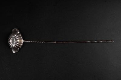 a silver spoon with a flower on it on a black surface