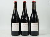 trois bouteilles de vin rouge posées l'une à côté de l'autre sur une surface blanche