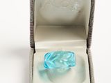 a blue glass ring in a box on a white surface
