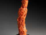 une statue sculptée dans de l'orange représentant une femme, posée sur un socle en bois