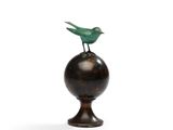 sculpture représentant un oiseau perché sur une boule, sur fond blanc