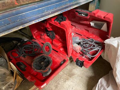 une boîte à outils rouge contenant des outils, posée par terre