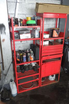 une étagère rouge dans un garage, sur laquelle sont posés des outils