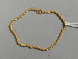 gros plan d'un bracelet en chaîne en or sur une surface grise