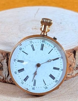 a gold pocket watch sitting on top of a piece of wood