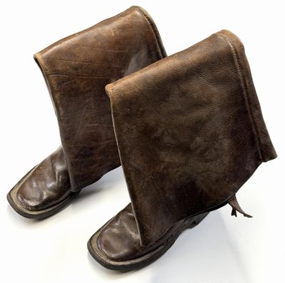 une paire de bottes en cuir marron posées sur une surface blanche, avec un fond blanc