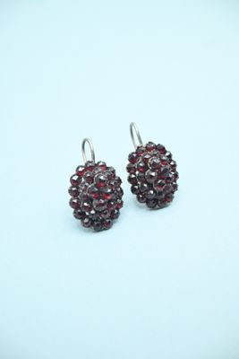 silver earrings with garnets on them on a blue background