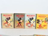 several mickey mouse books are lined up on a white surface