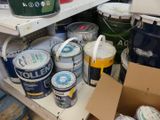 many cans of paint sitting on a shelf in a room