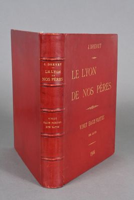 an old red book sitting on top of a table next to a gray wall