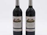 two bottles of red wine sitting next to each other on a white surface