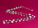 a close up of a necklace with pearls on a pink background
