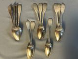 six cuillères en argent sont disposées en rangée sur une table