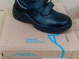 black leather shoes with velcro straps on top of a cardboard box