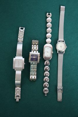trois montres et un bracelet de montre posés sur une table verte