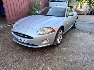 a picture of a silver sports car parked in front of a garage